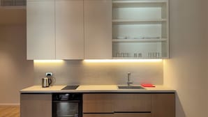 A modern kitchen with built-in cabinets, a dishwasher, and a countertop with a kettle and a red napkin.