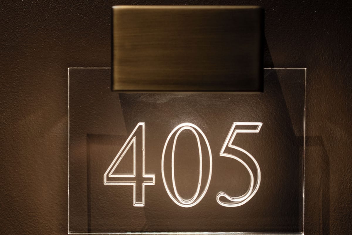Un numéro « 405 » bien visible et éclairé, affiché sur un mur, avec une poignée métallique au-dessus.