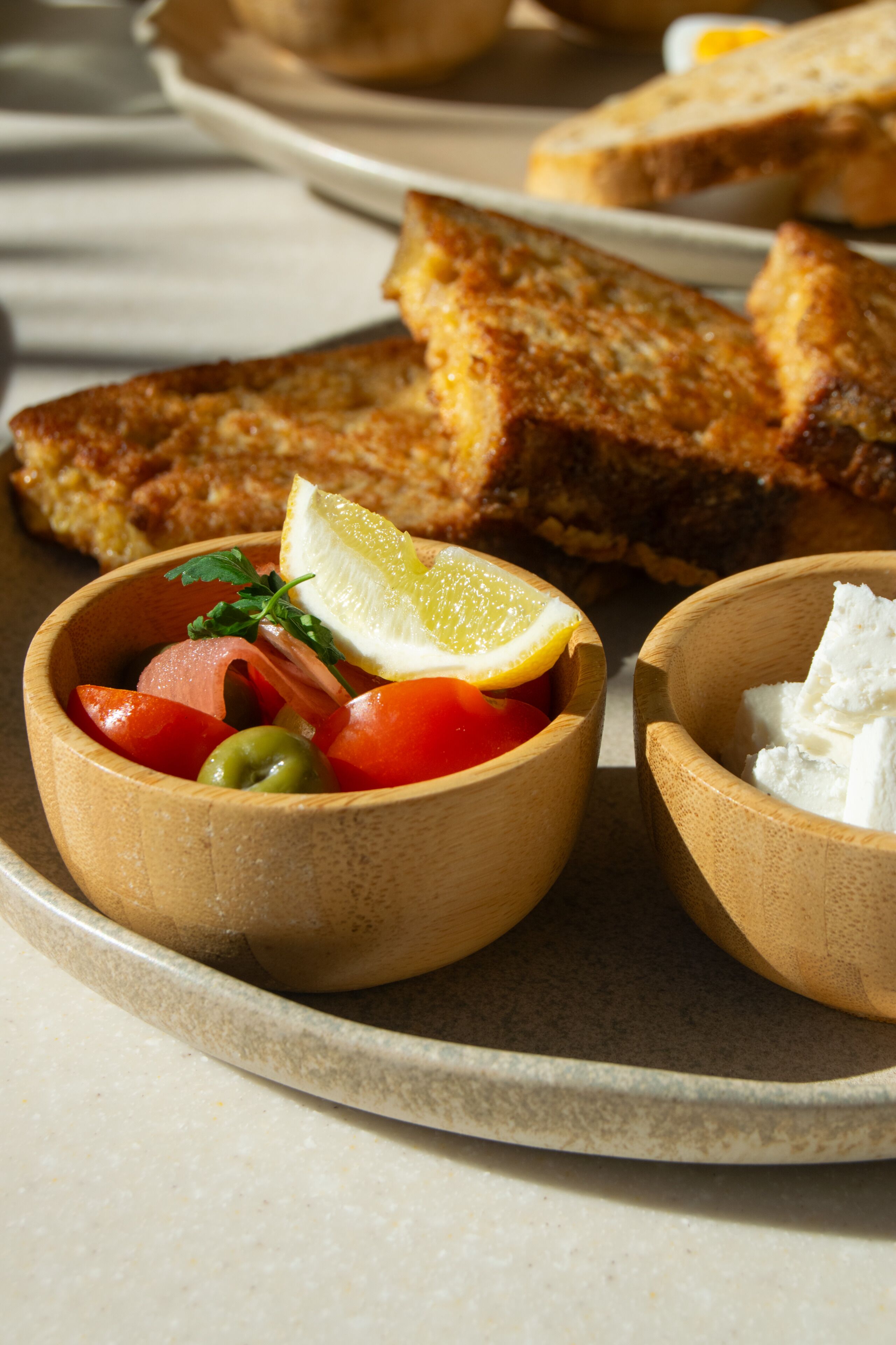 A tray with toasted bread, a bowl of vegetables, and a bowl of cheese.
