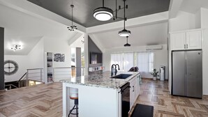A modern kitchen with a central island, stainless steel appliances, and a herringbone wood floor. - Beachside 9BR Oasis/Pickle Ball/Infrared Sauna (Sosúa)