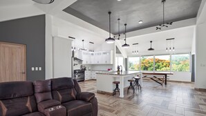 A spacious living area with a modern kitchen, a dining area with a large window, and a comfortable seating area. - Beachside 9BR Oasis/Pickle Ball/Infrared Sauna (Sosúa)