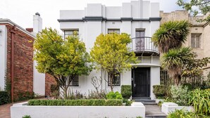 A two-story building with a white facade, black shutters, and a balcony. - Pet Friendly - Deco Days in Prahran (Prahran)