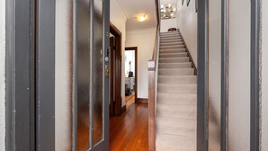 A hallway with a wooden floor, a carpeted staircase, and a door with a frosted glass panel. - Pet Friendly - Deco Days in Prahran (Prahran)