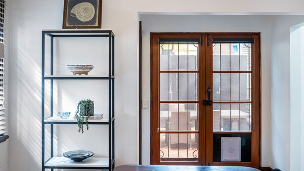 A room with a wooden door, a blue metal shelf with decorative items, and a window with blinds. - Pet Friendly - Deco Days in Prahran (Prahran)