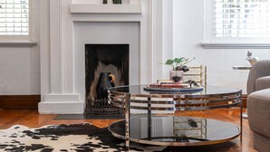 A modern living room with a round glass coffee table, a fireplace, and a cowhide rug. - Pet Friendly - Deco Days in Prahran (Prahran)