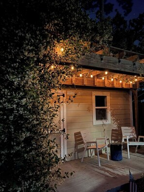 Une cabane en bois avec une véranda, des guirlandes lumineuses et des sièges d’extérieur.