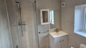 A bathroom with a glass-enclosed shower, a white sink, a mirror, and a window. - Modern Easedale House - 3 Bed House in Hornchurch (Hornchurch)
