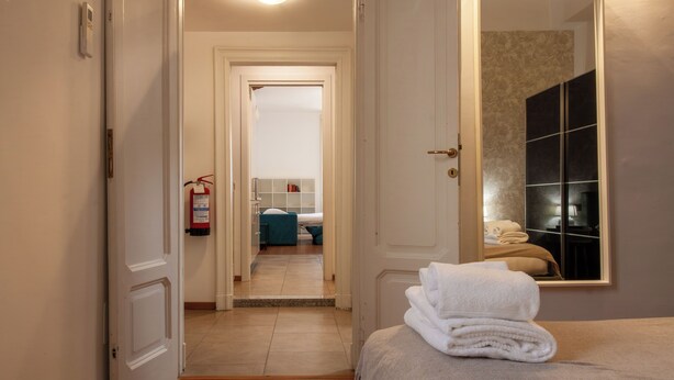 Een hotelkamer met een bed, een badkamer zichtbaar door een open deur en een brandblusser aan de muur.