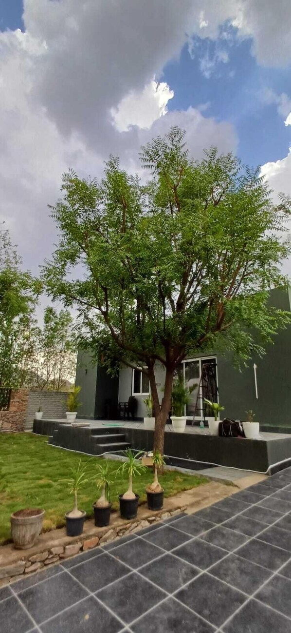 A modern house with a well-maintained lawn and a tree in the front yard. - Dheergarh Villa (Nathdwara)