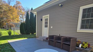 A patio with a round table and chairs, a small fire pit, and a covered seating area.