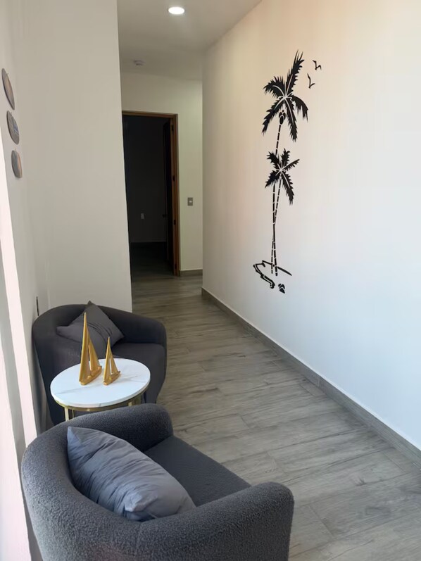 Una sala moderna con un sofá gris, una mesita redonda y barcos decorativos.