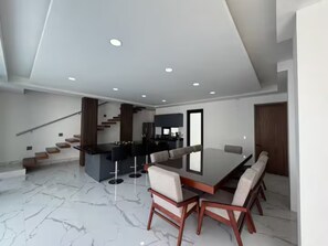 Un interior moderno con comedor, cocina y escalera.