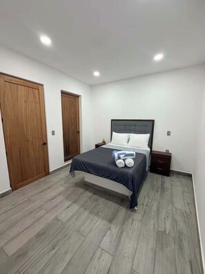 Un dormitorio con cama, armario de madera y mesita de noche.