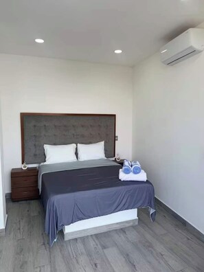 A modern bedroom with a bed, bedside tables, and an air conditioning unit.