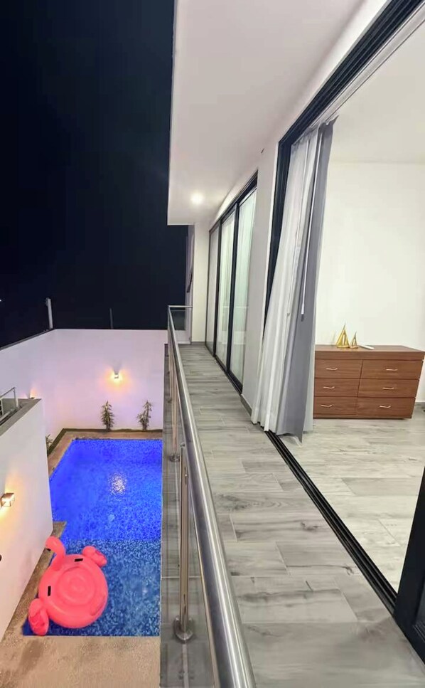 Un balcón moderno con piscina, un armario de madera y barandilla.