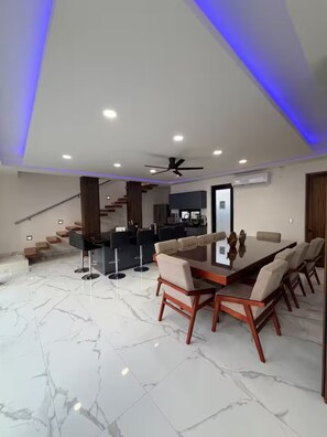 Un interior moderno con comedor, cocina y escalera.