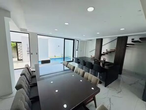 Un interior moderno con comedor, cocina y vista a una piscina exterior.