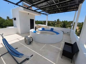 Una terraza en la azotea con un área de estar circular, una hamaca y una pequeña mesa.