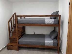 Una cama litera con estructura de madera y ropa de cama gris.