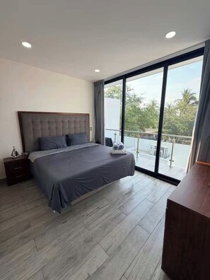 Un dormitorio con una cama grande, una mesita de noche, un aparador de madera y un balcón con vistas.