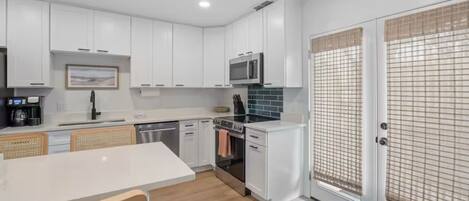Una cocina moderna con armarios blancos, un microondas, una estufa y un lavamanos.