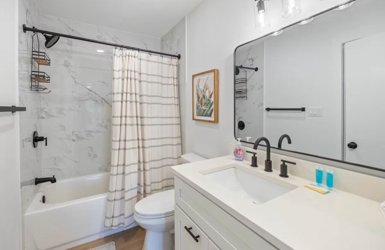 Un baño moderno con bañera, inodoro y un espejo grande.