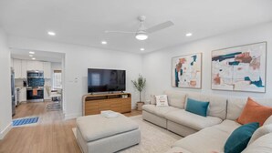 Una sala de estar moderna con sofá, reposapiés y televisor de pantalla plana.