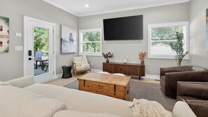 A modern living room with a large flat-screen TV, a wooden coffee table, and a sofa.