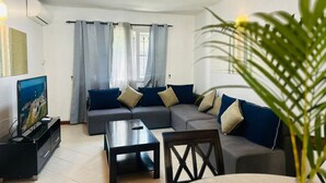 A modern living room with a sectional sofa, a coffee table, a TV, and a potted plant.