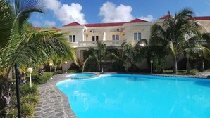A swimming pool surrounded by palm trees and a building with a red roof.