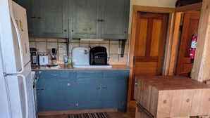 Una cocina con armarios azules, un refrigerador blanco, un tostador y una mesa de madera.