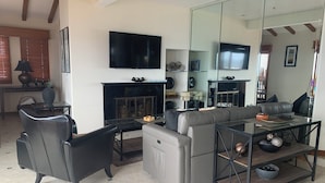 Una sala de estar moderna con chimenea, un sofá, una mesa de centro y un televisor montado en la pared.