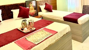 Une chambre d’hôtel avec deux lits, chacun agrémenté de draps rouges et blancs, d’une tête de lit en bois et d’une petite statue de Bouddha placée sur le lit de gauche.