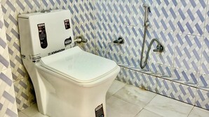 Une salle de bain avec des toilettes blanches, une douche et des carreaux décoratifs sur les murs.
