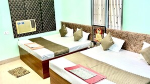 Une chambre d’hôtel avec deux lits, une fenêtre avec des barreaux, un climatiseur fixé au mur et un papier peint à motifs.