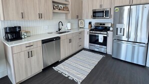 Eine moderne Küche mit hellen Holzschränken, Edelstahlgeräten und einem dunklen Holzboden.