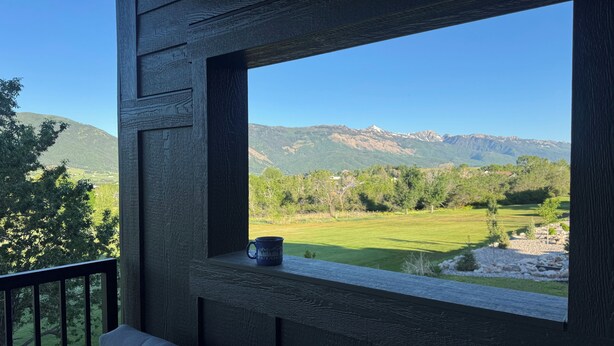 Ein hölzerner Balkon mit Blick auf ein grünes Feld und Berge.