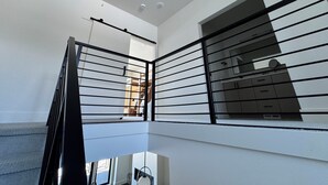 Ein modernes Interieur mit einer Treppe, weißen Wänden und einem schwarzen Geländer.