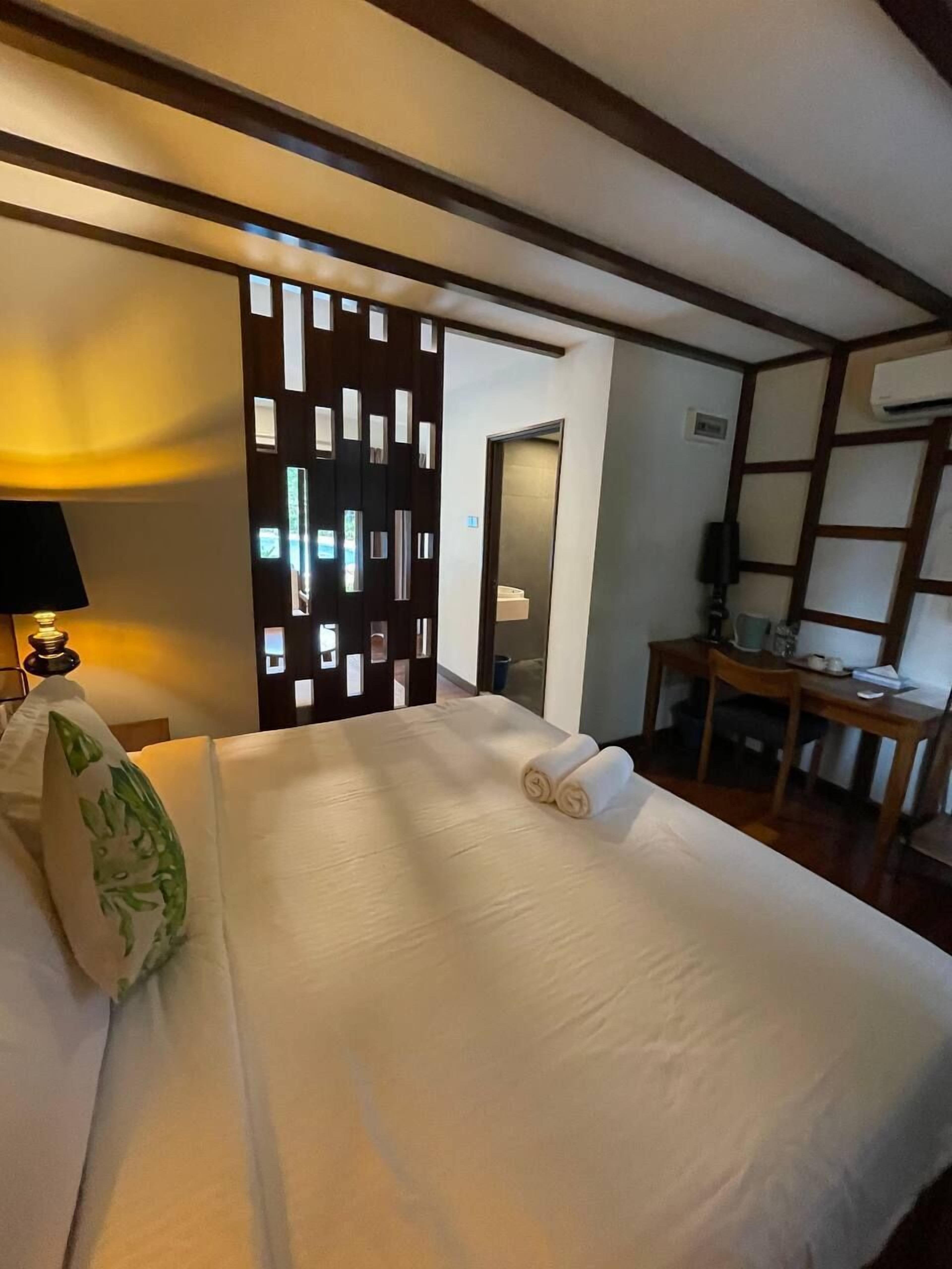 Une chambre d’hôtel avec un lit bien fait, un bureau avec une chaise, une lampe et un panneau décoratif.