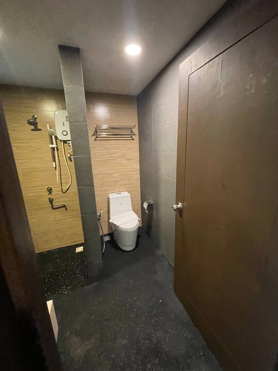 Un baño pequeño con ducha, inodoro y un perchero para toallas.