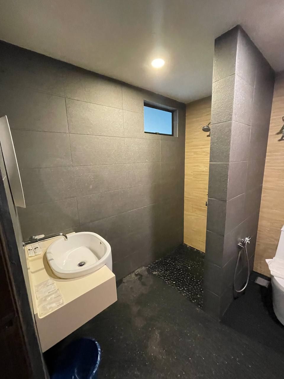 A modern bathroom with a built-in sink, a shower area, and a small window.