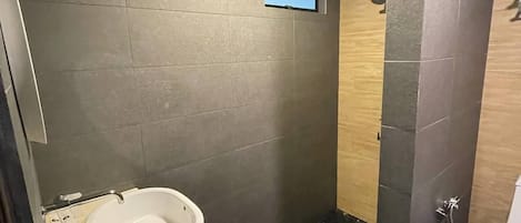 A modern bathroom with a built-in sink, a shower area, and a small window.