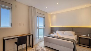 A modern hotel room with a large bed, bedside tables, a desk, and a view of the sea. - 3-bedroom Apartment 170m From the Beach Gua1902 (Balneário Camboriú)