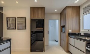 A modern kitchen with a built-in oven, a black countertop, and wooden cabinetry. - 3-bedroom Apartment 170m From the Beach Gua1902 (Balneário Camboriú)
