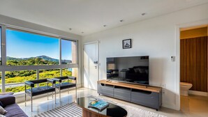 A modern living room with a large TV, a sofa, and a coffee table. - 3-bedroom Apartment 170m From the Beach Gua1902 (Balneário Camboriú)