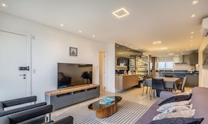 A modern living room with a flat-screen TV, a coffee table, and a sofa. - 3-bedroom Apartment 170m From the Beach Gua1902 (Balneário Camboriú)