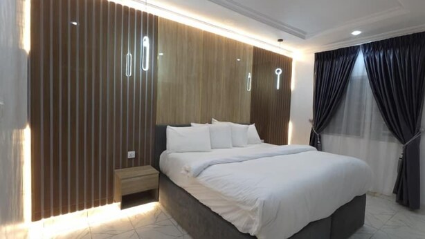 Une chambre à coucher moderne avec un grand lit, des lambris en bois sur les murs et une table de chevet.