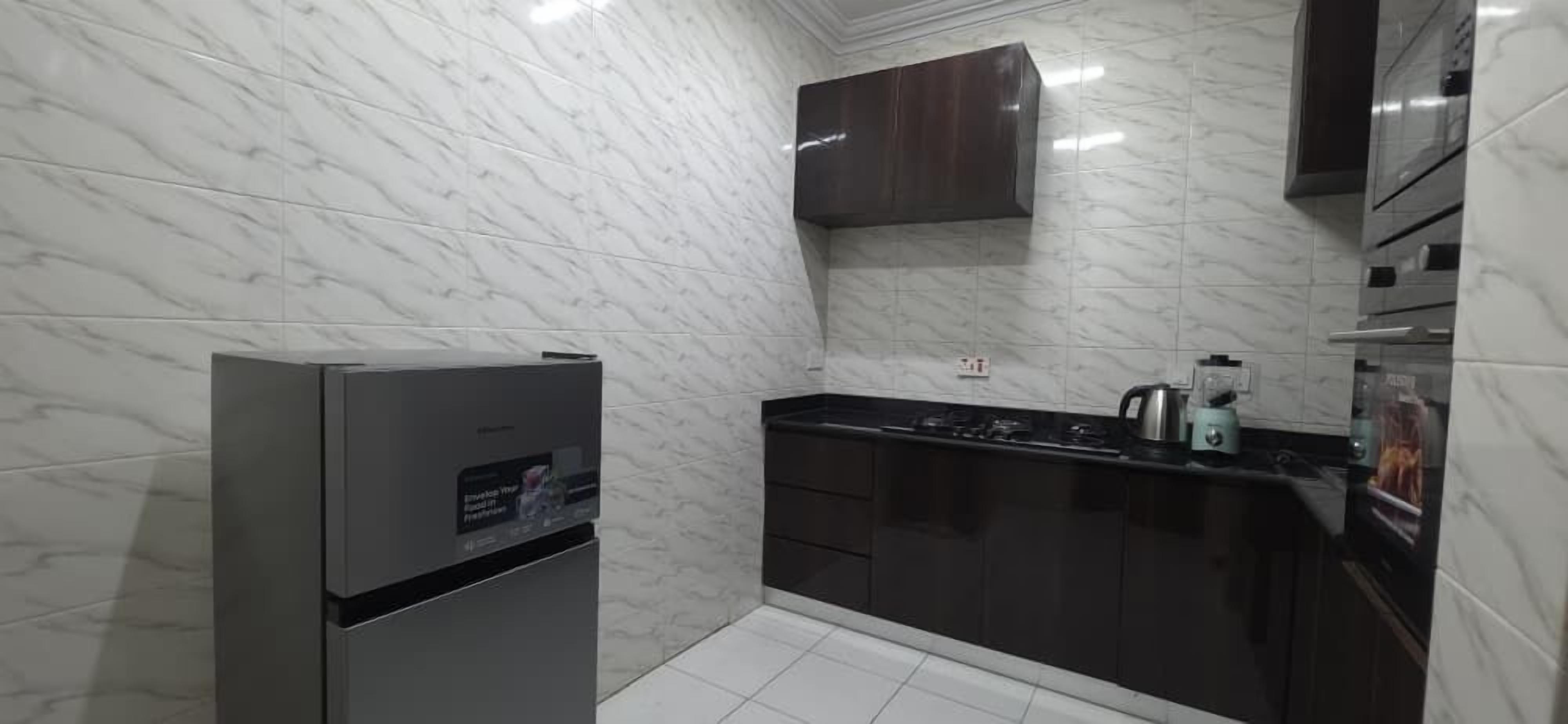 A modern kitchen with marble walls, a built-in stove, and dark cabinetry.
