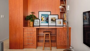 Un bureau en bois avec des tiroirs, un tabouret et des tableaux encadrés.