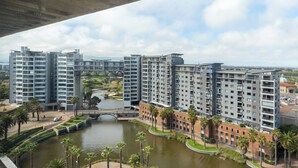 Un ensemble d’immeubles résidentiels de grande hauteur, dotés de nombreux balcons, d’un élément décoratif central avec de l’eau et d’un pont en arrière-plan.